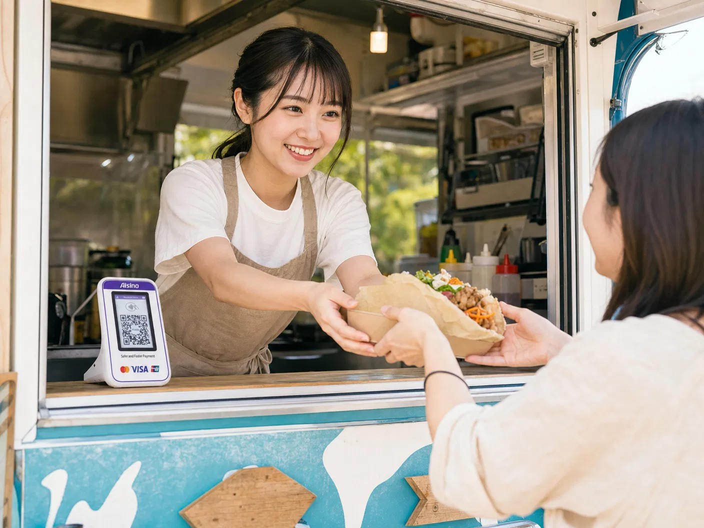 キッチンカーでFinGoの決済端末を使い、料理を受け渡す様子